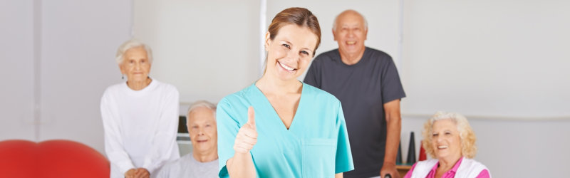 caregiver and group of elderly smiling